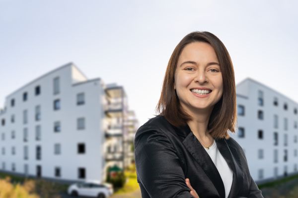 Eine Mitarbeiterin vor zwei Gebäuden.