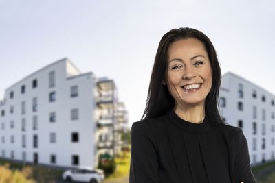 Eine Mitarbeiterin vor zwei Gebäuden.