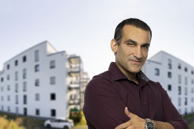 Ein Mitarbeiter vor zwei Gebäuden.