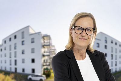 Eine Mitarbeiterin vor zwei Gebäuden.