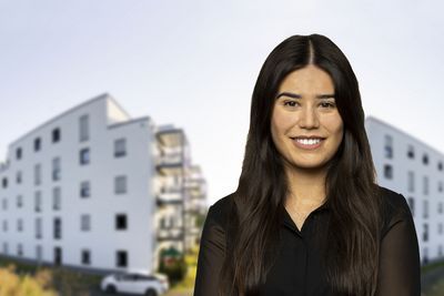 Eine Mitarbeiterin vor zwei Gebäuden.