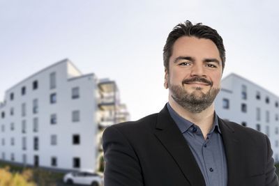 Ein Mitarbeiter vor zwei Gebäuden.