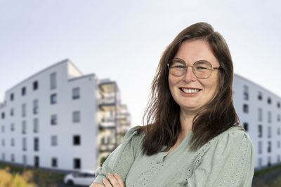 Eine Mitarbeiterin vor zwei Gebäuden.