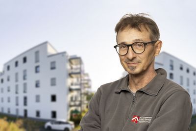 Ein Mitarbeiter vor zwei Gebäuden.