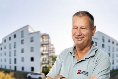 Ein Mitarbeiter vor zwei Gebäuden.